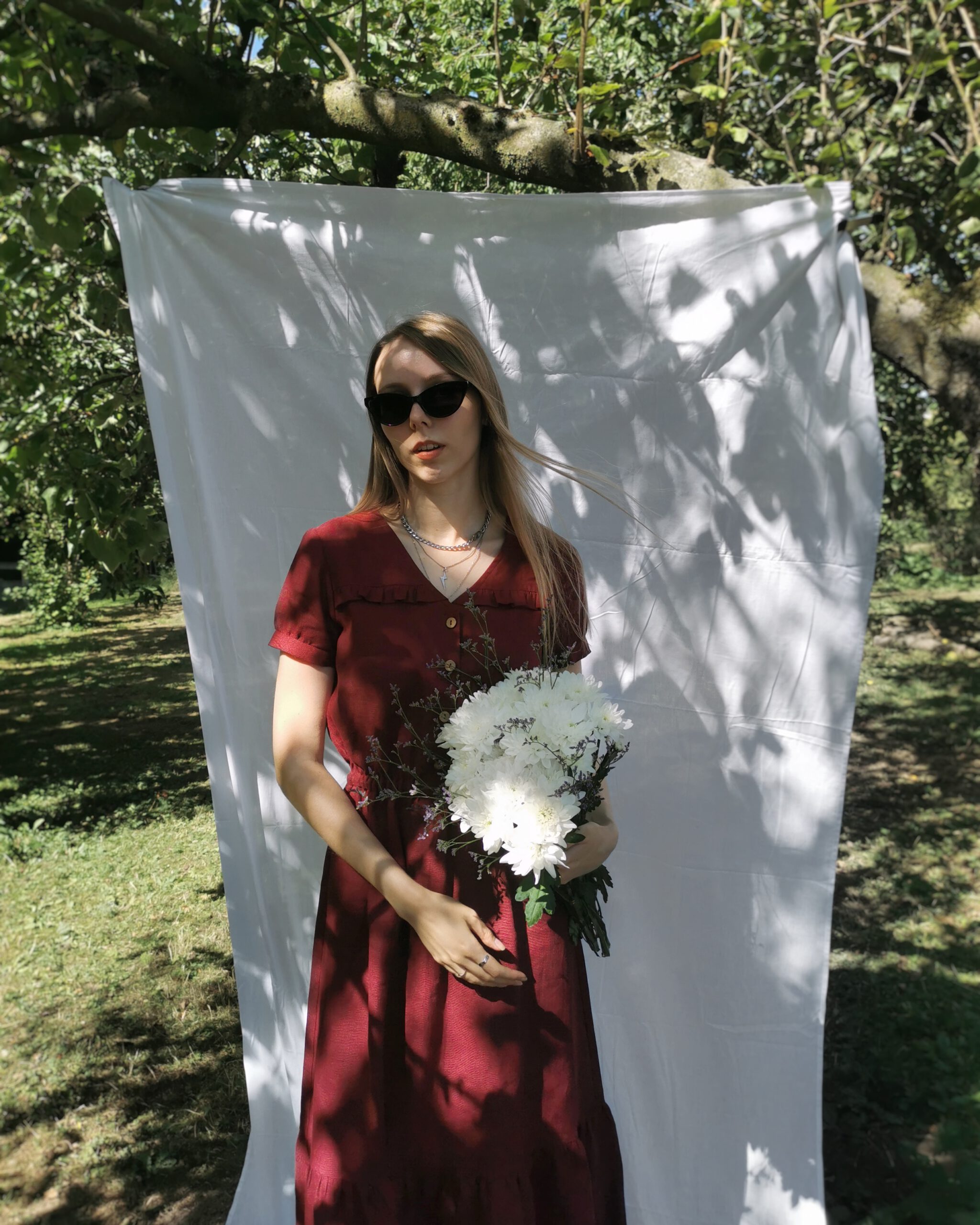 Linnen jurk wijnrood op maak gemaakt door Naaiatelier Marta in Breda cottagecore fotoshoot met wit doek in natuur met romantische sfeer en witte bloemen